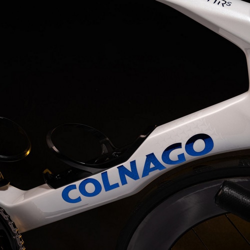 Colnago Y1RSのフレーム部分をクローズアップした画像。ホワイトのエアロフレームにブルーの「COLNAGO」ロゴが映え、革新的なデザインと空力性能を強調。ボトルケージが内蔵され、整流性向上が図られている。